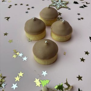 Vier mini notentaartjes met knapperige bodem en hazelnoot-chocoladetopping met zilveren parel, feestelijk gepresenteerd.