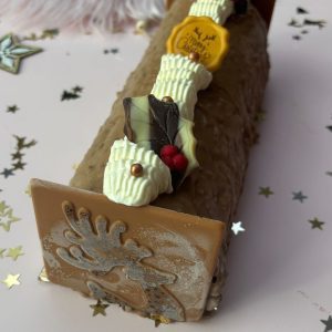 Hazelnoot ijsparfait taart met chocolade, koffiecrunch en roomdecoratie – feestelijke bûche met karamelchocolade rendier.